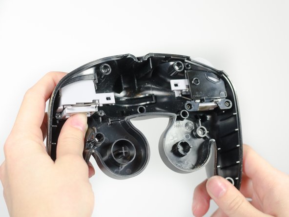 Hold the grey square bracket onside of the controller with your thumb.