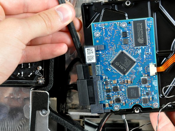 Insert the flat end of a spudger between the SATA data cable and the edge of the hard drive.