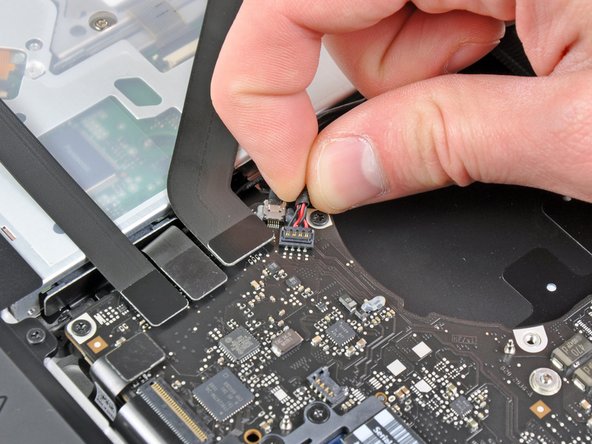 Image 2/2: Pull the right speaker/subwoofer cable upward to lift the connector out of its socket on the logic board.