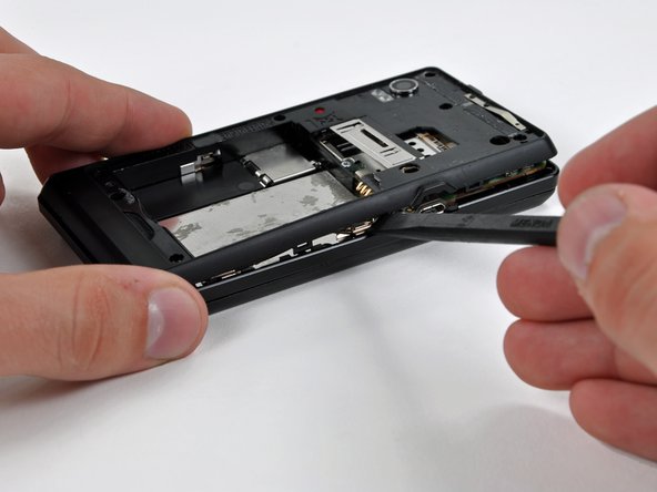 With the spudger still inserted between the rear case and front case, slide the spudger along the right edge of the device, moving toward the bottom, prying as you go.