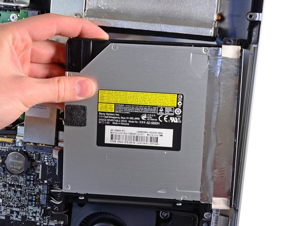 Image 1/2: Carefully pull the optical drive off its mounting pins on the right side of the outer case to gain clearance for disconnecting the optical drive cable.