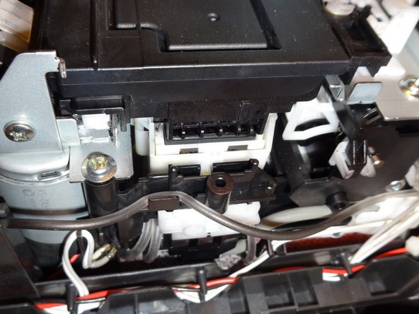 Using a spudger, press down on the plastic housing of the park carriage that the print head rests on.