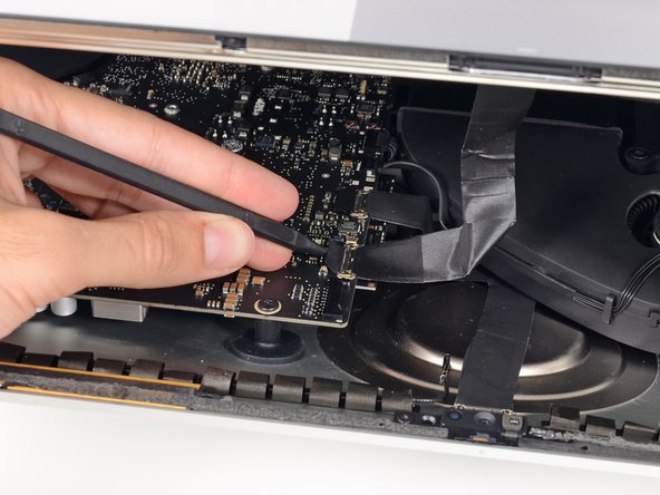 Image 1/3: Carefully pull the display data cable from its socket on the logic board.