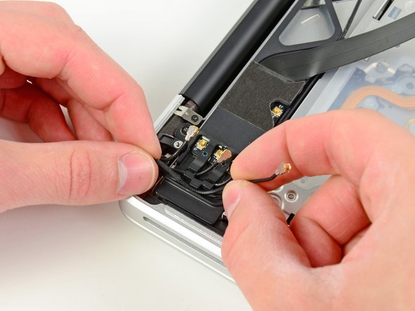 Image 1/3: De-route the camera cable from its channel in the AirPort/Bluetooth housing.