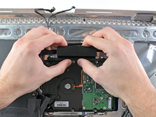 Image 1/2: Pull the top edge of the hard drive slightly away from the rear case.