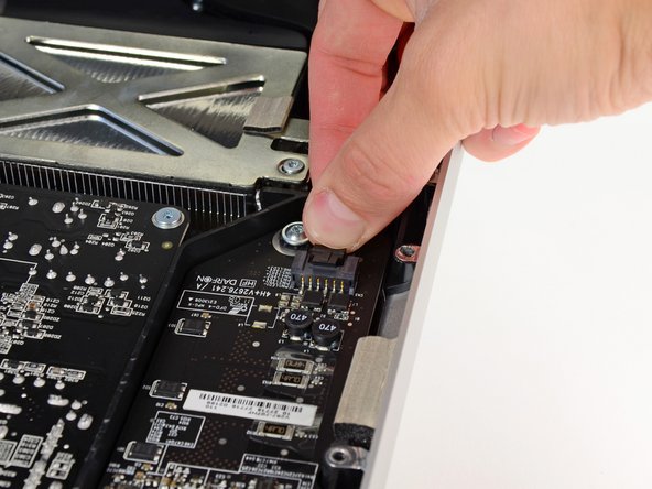 Image 2/2: Disconnect the LED backlight power cable by depressing the locking mechanism while pulling the connector away from its socket (toward the bottom edge of the iMac).