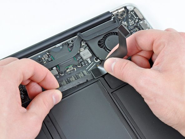 Image 2/2: While gently pulling the I/O board cable upward near its connection to the logic board, use the tip of a spudger to pry upward on alternating sides of the connector to help "walk" it out of its socket.