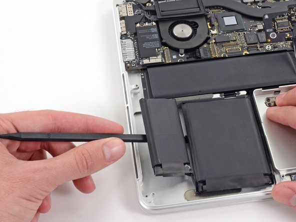 Image 2/3: Run the spudger down along the leftmost battery cell.