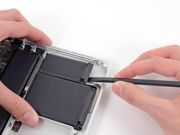 Image 2/3: Wedge the flat end of a spudger underneath the bottom portion of the rightmost battery cell.