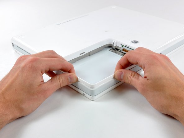 Image 1/1: Push in the thin rims of the lower case surrounding the battery compartment, bending them past the tabs, and then lift up to free that corner of the lower case.