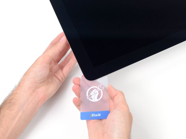 Image 2/3: Starting from the top right corner of the iMac, wedge a plastic card between the display and frame.
