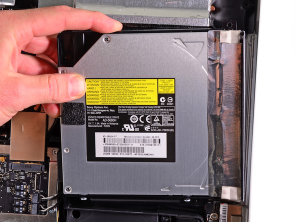 Image 1/2: Carefully pull the optical drive off its mounting pins on the right side of the outer case to gain clearance for disconnecting the optical drive cable.