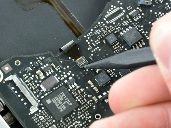 Image 1/2: Using the tip of a spudger, flip up the keyboard backlight ribbon cable retaining flap.