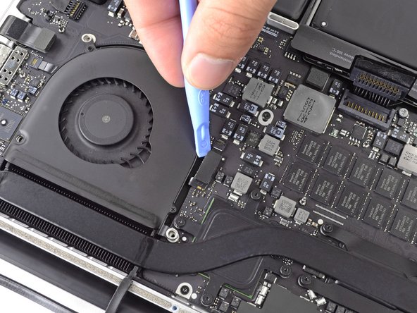 Image 2/3: Starting at the top of the cable, slide a plastic opening tool under the left fan cable to free it from the logic board.