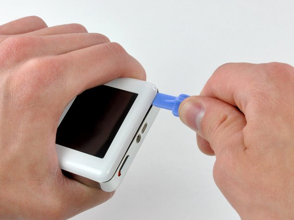 Image 2/2: Run the tool along the top seam toward the upper left corner of the iPod.  Press the tool into the corner, creating a small gap on the side of the case.