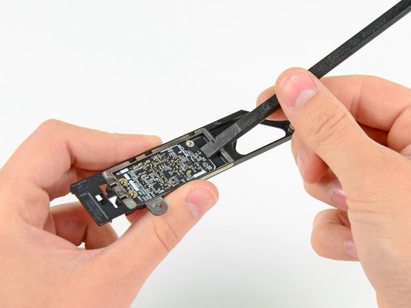 Image 2/2: Use the flat end of a spudger to dislodge the AirPort/Bluetooth board from its recess in the AirPort/Bluetooth board housing.
