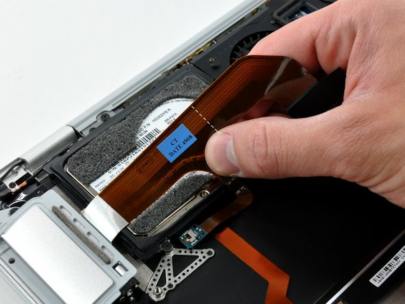 Image 2/2: If necessary, pull the audio out ribbon cable off the adhesive securing it to the upper case.