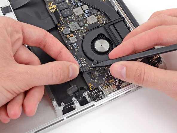 Image 2/3: Grasp the plastic pull tab and pull the microphone ribbon cable out of its socket.