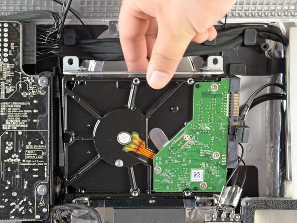 Image 2/2: Lift the hard drive off its two lower positioning pins and remove it from the outer case.