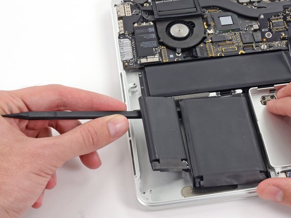 Image 1/3: Run the spudger down along the leftmost battery cell.
