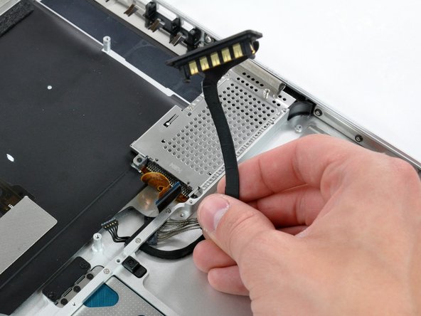 Image 2/2: De-route the battery connector cable through the gap in the upper case and remove it from the computer.