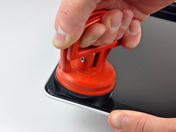 Image 1/3: Use the flat end of a spudger to gently pry up the adhesive securing the front glass to the display.