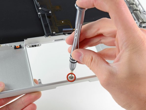 Image 1/1: Use a T6 Torx screwdriver to loosely install the 1.1 mm set screw included with your new upper case into its tapped hole near the middle of the trackpad opening on your new upper case.
