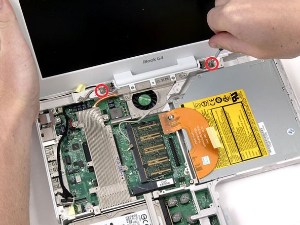 Support the display with one hand and remove the single Phillips screw on either side of the hinge (two screws total).