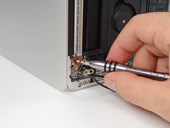 Image 1/1: While holding the display and upper case together with your left hand, remove the remaining T8 Torx screw from the lower (closer to the table) display bracket.