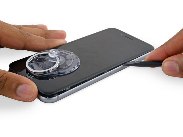 Slide the spudger up the right side to continue separating the adhesive and popping the display clips free from the iPhone.