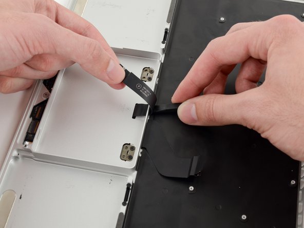 Image 2/2: Run the spudger along the bottom to release the trackpad ribbon cable from the adhesive securing it to the upper case.