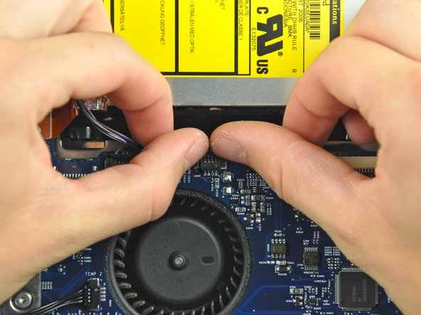 Image 2/2: To aid in removal, it is helpful to use both of your thumbnails to push the ears on either side of the connector toward the top edge of the iMac.