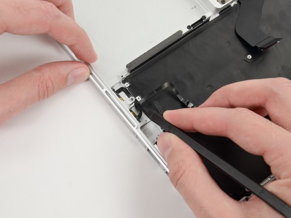 Image 2/3: Run the spudger up along the bottom of the microphone assembly cable to separate it from the upper case.