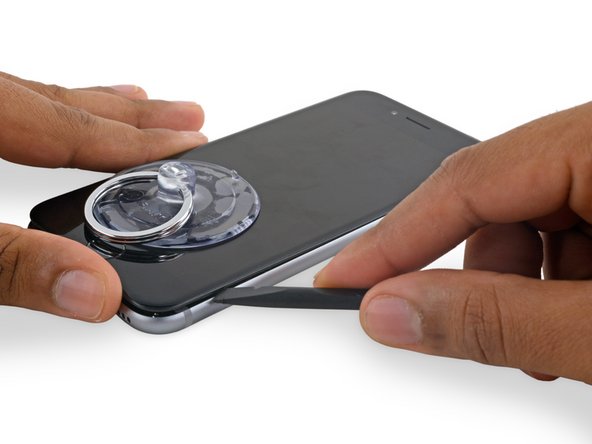 Slide the spudger up the right side to continue separating the adhesive and popping the display clips free from the iPhone.