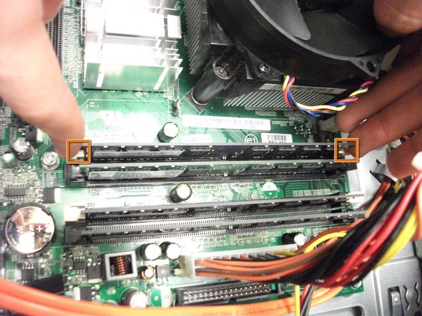 Image 1/1: Locate the two plastic tabs on the ends of a RAM stick.