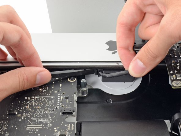 Image 2/3: While pressing on the release clip with the spudger, grasp the AC inlet cable, and pull the connector straight out of its socket.