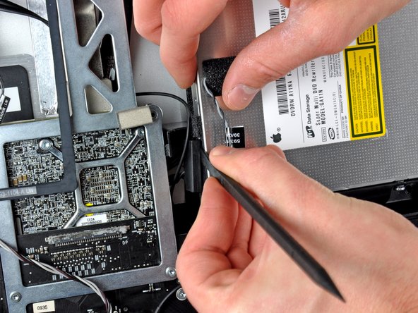 Image 2/2: Twist the spudger to slightly separate the optical drive connector from the optical drive, then use your fingers to pull the connector away from the drive.