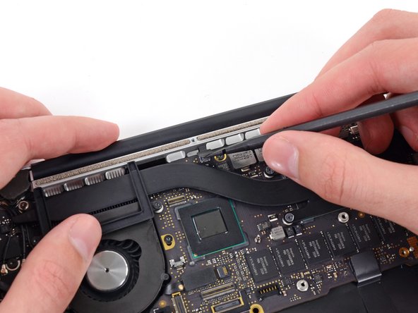 Image 2/2: Gently twist the flat end of a spudger upwards to pry the keyboard backlight connector up off its socket on the logic board.