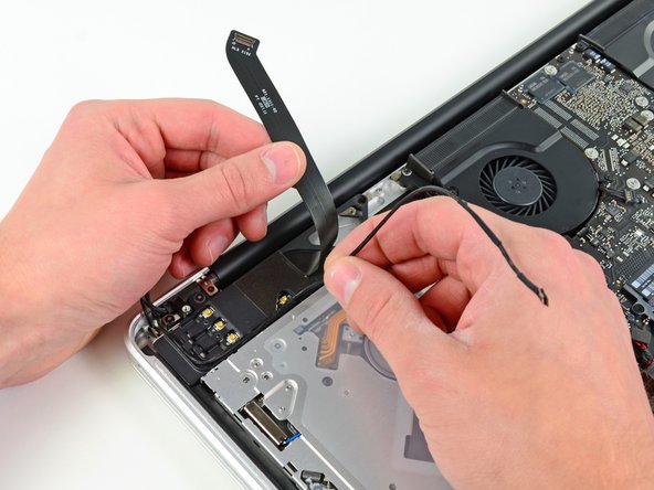 Image 3/3: De-route the camera cable from its channel in the AirPort/Bluetooth housing.