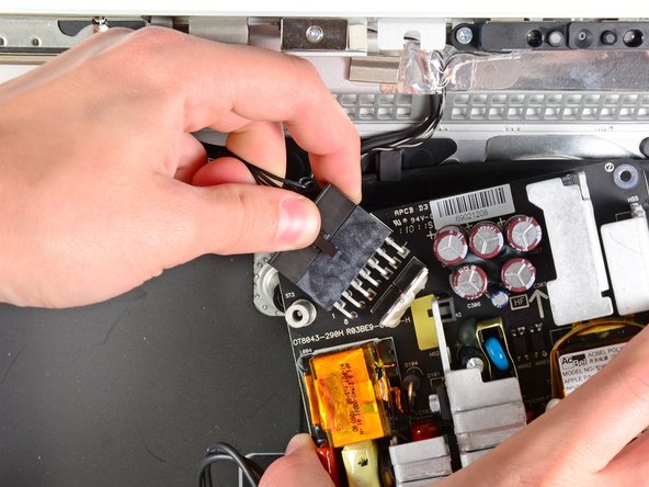 Image 1/2: Disconnect the DC-out cable by depressing the locking mechanism on the connector while you pull the connector away from its socket on the power supply.