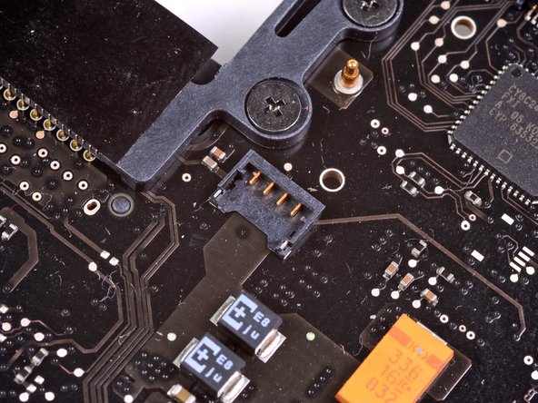 Image 2/3: The fan socket and the fan connector can be seen in the second and third pictures. Be careful not to break the plastic fan socket off the logic board as you use your spudger to lift the fan connector straight up and out of its socket. The layout of the logic board shown in the second picture may look slightly different than your machine but the fan socket is the same.