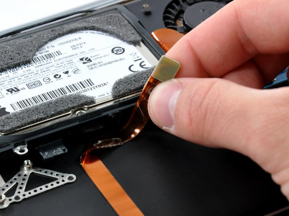 Image 2/2: Peel the audio cable off the adhesive securing it to the upper case.