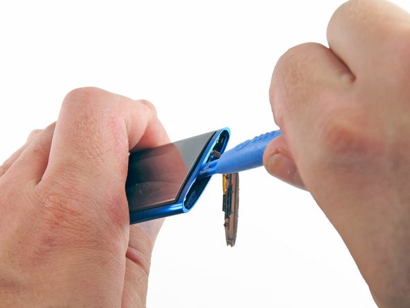 Image 1/2: Insert an iPod opening tool between the display and the glass panel at the top of the device.