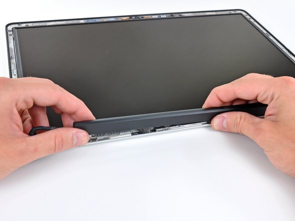 Image 1/2: Working from right to left, carefully continue to release and lift the clutch along the lower edge of the display assembly.