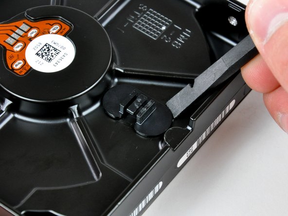 Use the flat end of a spudger to pry the hard drive thermal sensor bracket up off the adhesive securing it to the hard drive.