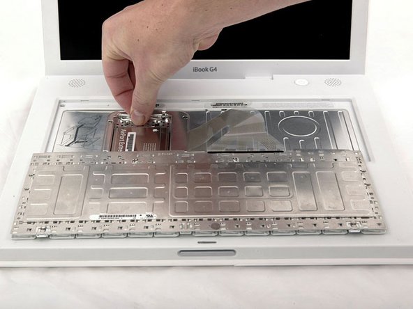 Image 1/1: Push the wire clasp away from the AirPort card and toward the display, then rotate up to free it from the RAM shield.