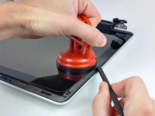 Image 2/2: Pull up on the glass panel while you use the flat end of a spudger to separate it from the rest of the display assembly.
