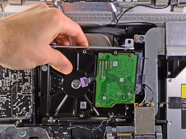 Image 1/1: Be careful not to contact the AirPort card as you lift the hard drive out of its recess.