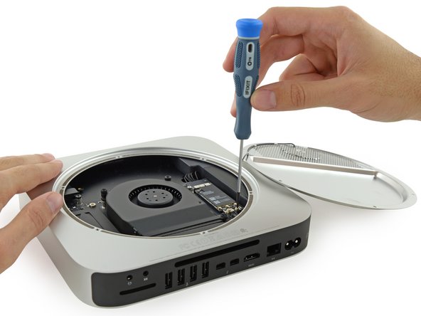 Image 2/2: Unfortunately, we're not home free yet. One end of the Wi-Fi antenna cable is clamped firmly to the plate, while the other end is screwed down onto the logic board.