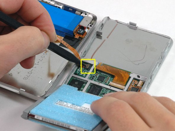 Lift the hard drive up with one hand so you can access the headphone jack ribbon beneath.